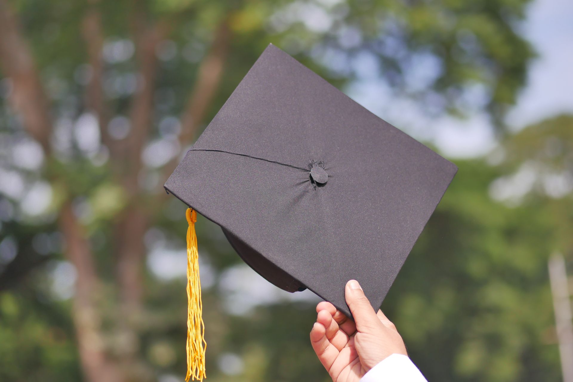 A hand holding up a graduation cap